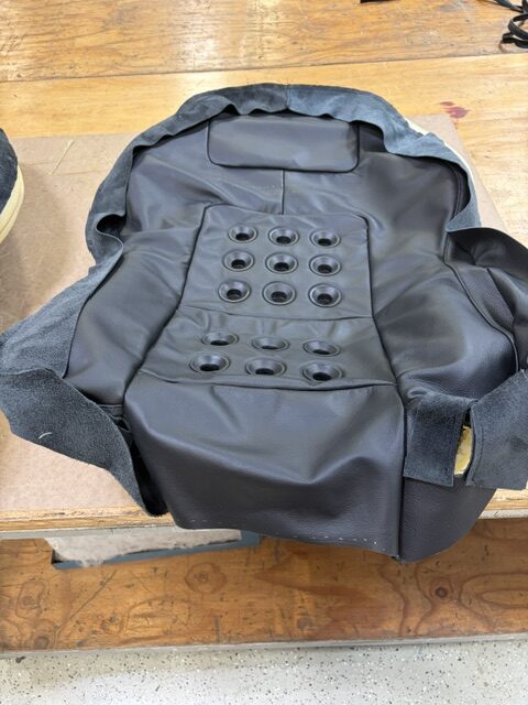 New black leather cover for a performance seat back, sewn with perforated pads, on the cutting table.
