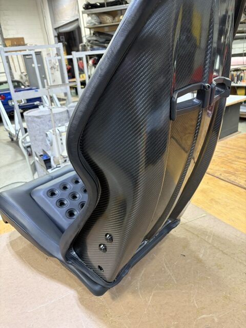 Carbon fiber shell of a performance seat after its black leather cover was fitted.